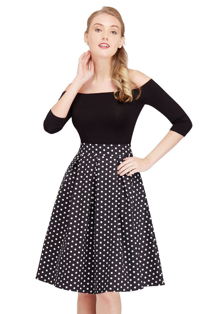 Model wears our high waisted swing skirt, in black, with white polka dots, close up view