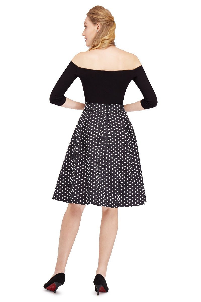 Model wears our high waisted swing skirt, in black, with white polka dots, back view