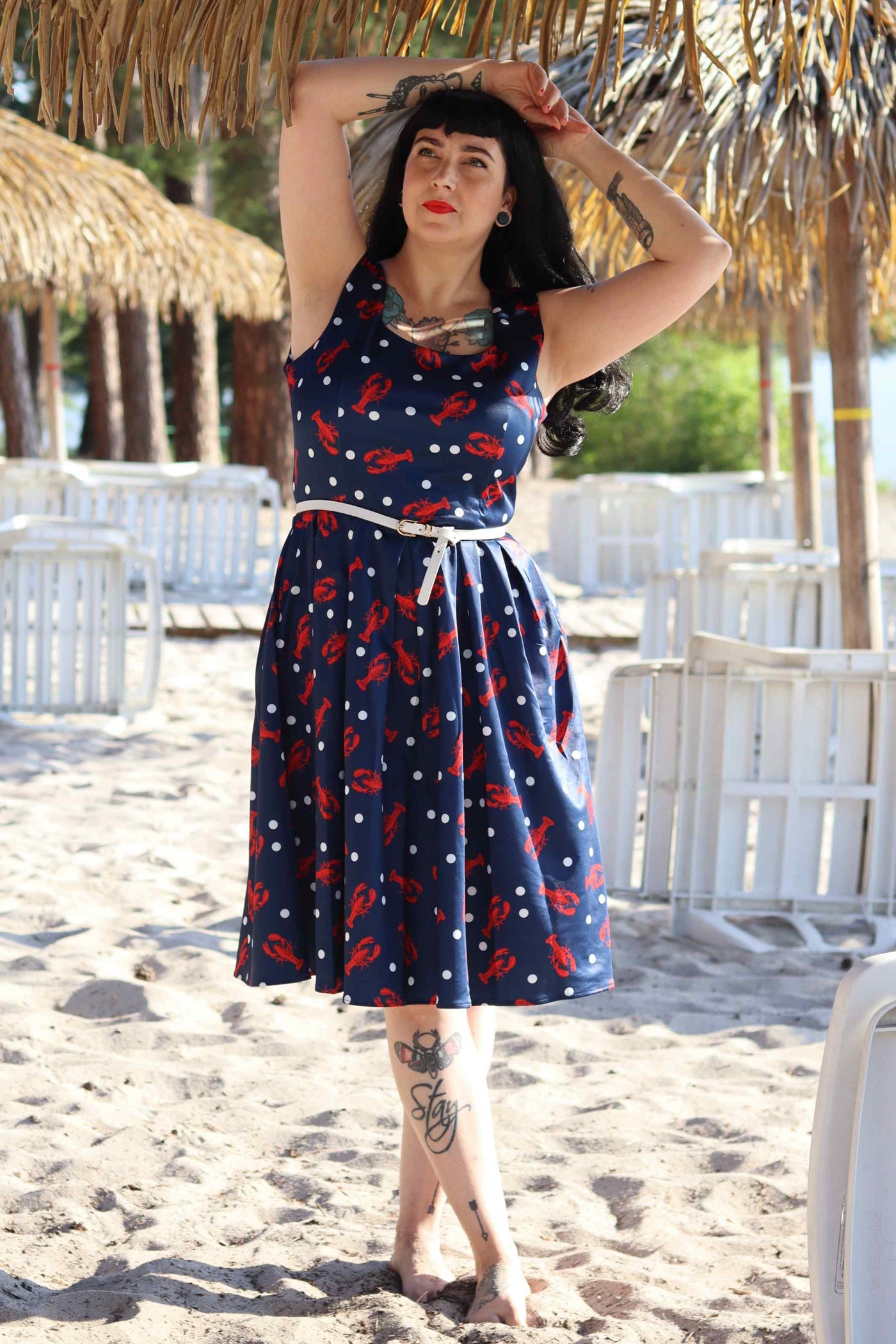 A lady wearing a Amanda 50s Inspired Navy Swing Dress with Red Lobsters and White Dots