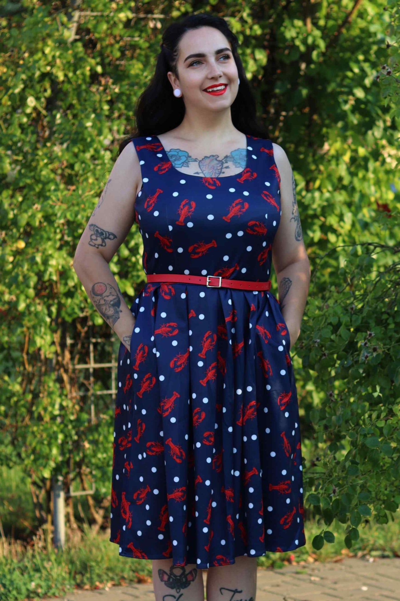 A lady wearing a Amanda 50s Inspired Navy Swing Dress with Red Lobsters and White Dots