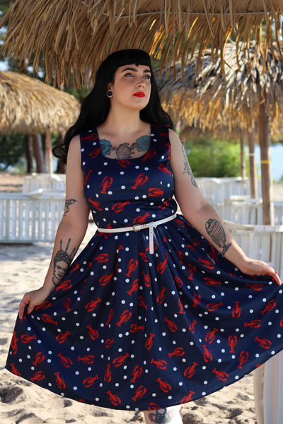 A lady wearing a Amanda 50s Inspired Navy Swing Dress with Red Lobsters and White Dots