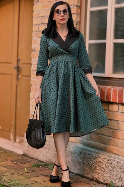 A lady wearing a Coat Dress in Green & Black Polka Dots