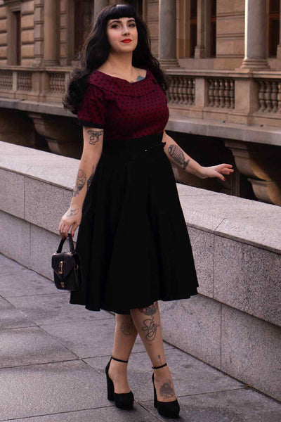 A lady wearing a Full Circle Swing Dress in Burgundy Polka-Black