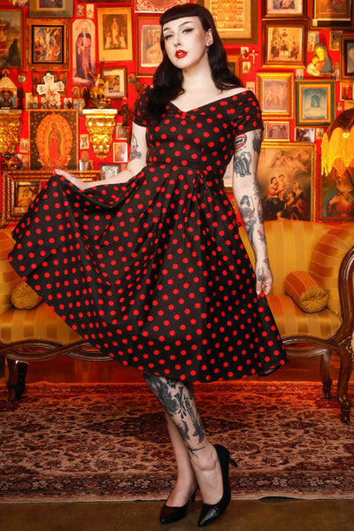 A model wearing a Rockabilly Polka Dot Off Shoulder Swing Dress In Black & Red