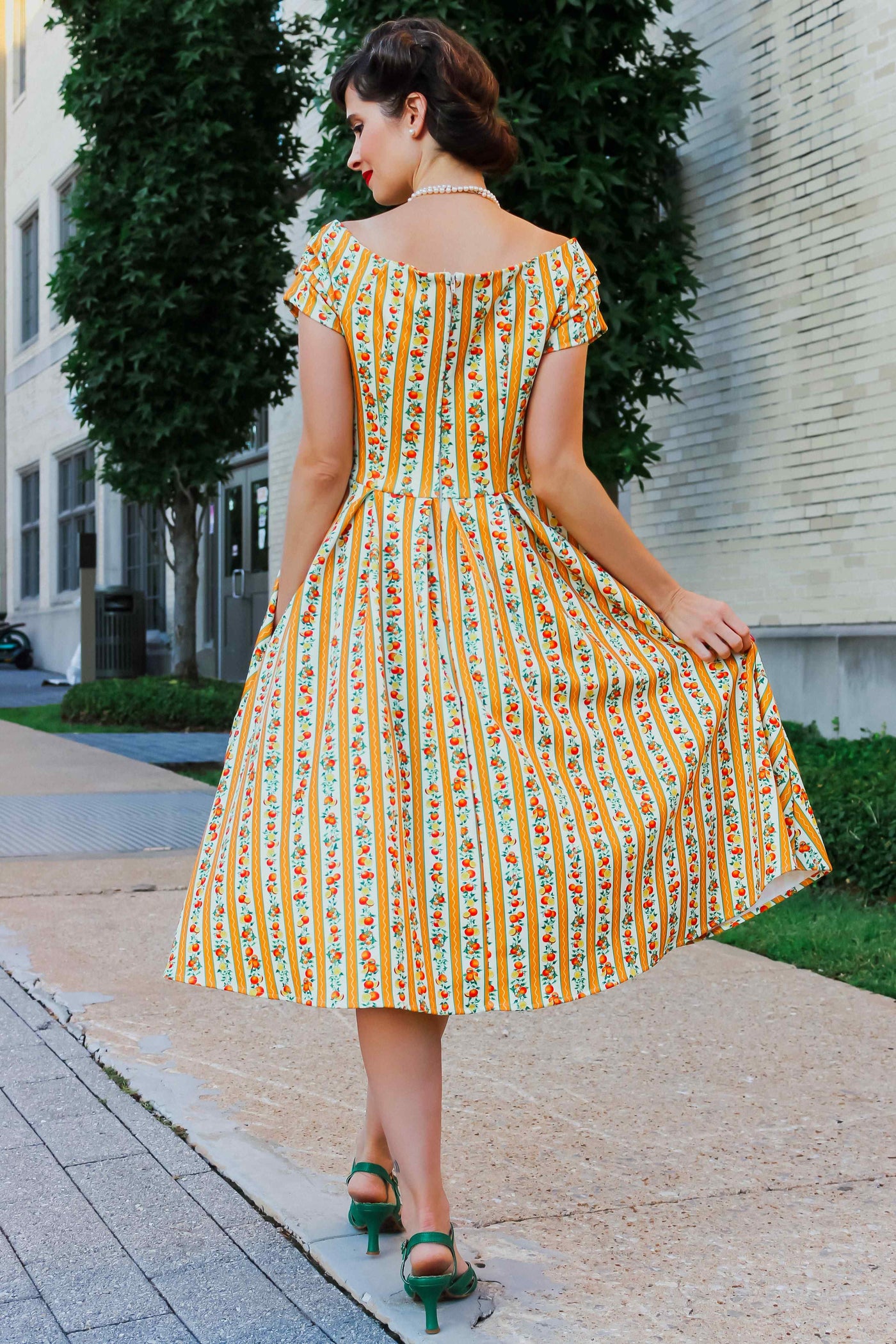 A model wearing a Sicilian Orange Stripe Swing Dress