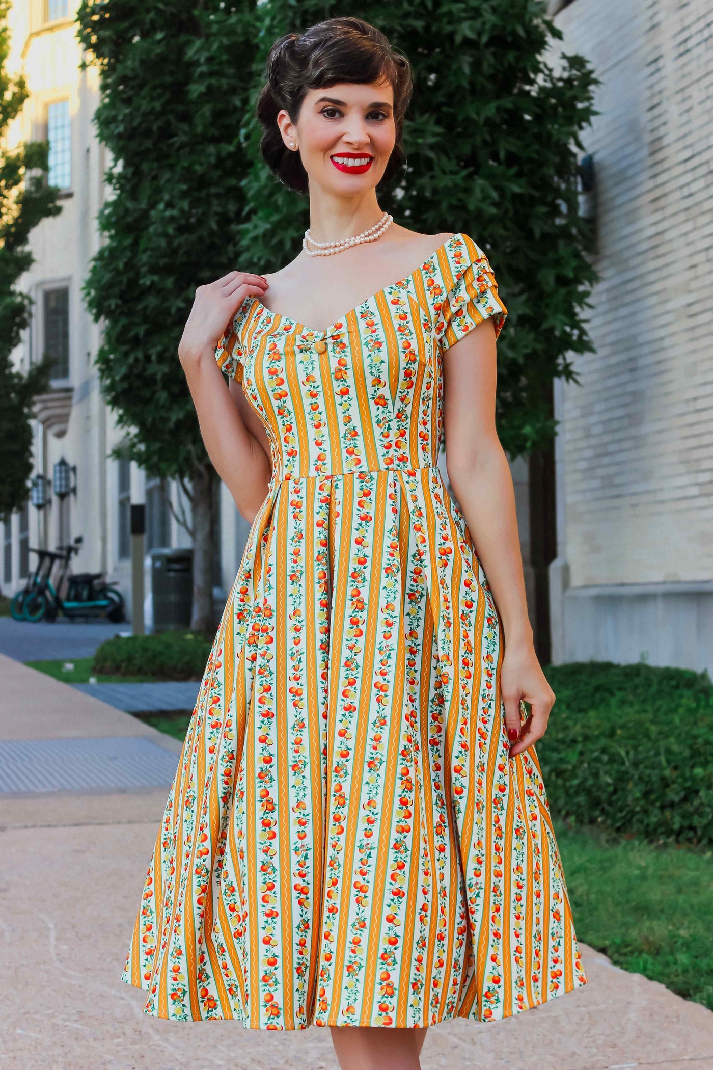 A model wearing a Sicilian Orange Stripe Swing Dress